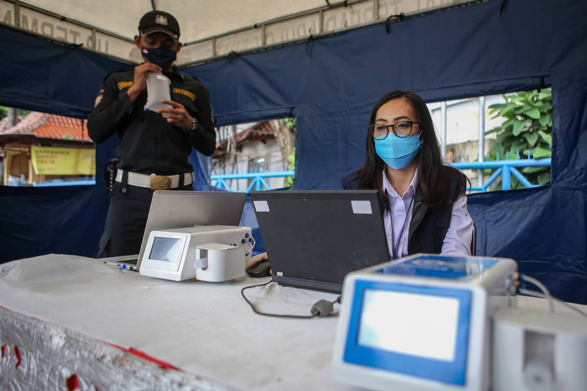 Petugas keamanan menghembuskan napasnya pada kantong untuk dites dengan GeNose C19 di Terminal Kampung Rambutan, Jakarta.