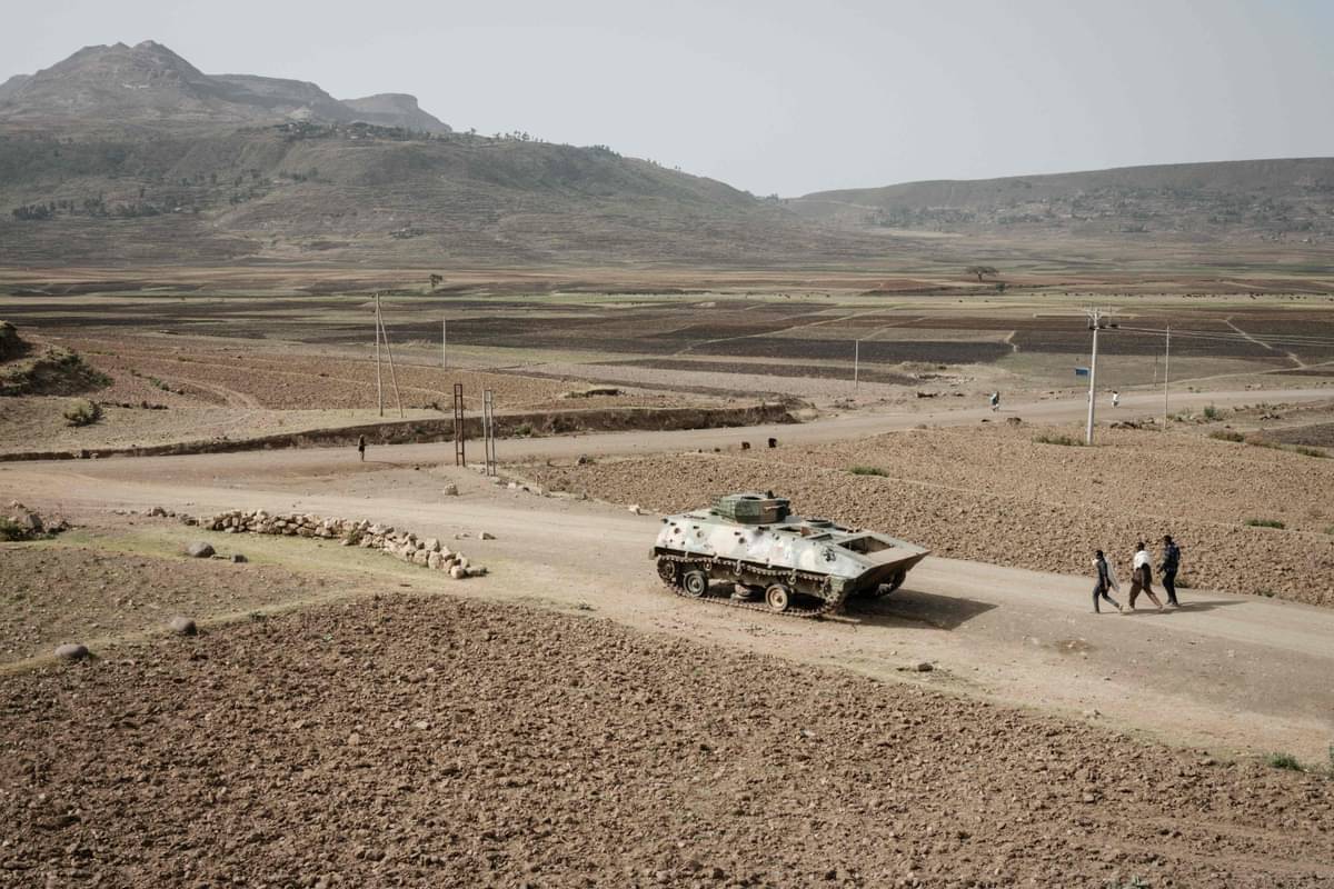 Warga berjalan tak jauh dari tank yang ditinggalkan di jalan dekat Dengolat, barat daya Mekele di wilayah Tigray, Ethiopia.
