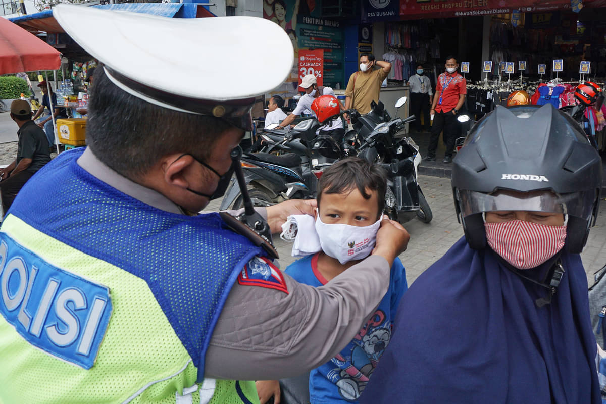 Ilustrasi. Anggota Satlantas Polres Karawang membantu memakaikan masker kepada seorang anak saat Operasi Keselamatan Lodaya 2022 di Karawang