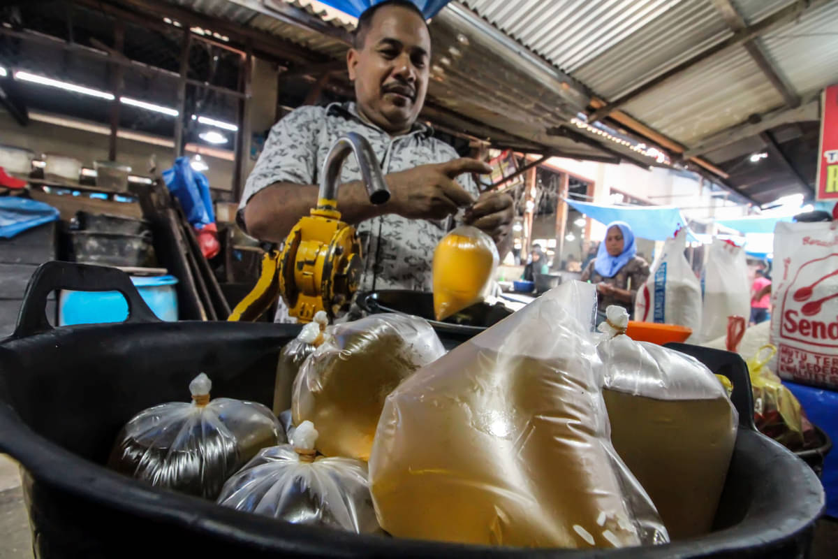 Pedagang membungkus minyak goreng curah eceran di pasar tradisional Inpres, Lhokseumawe, Aceh, Jumat (25/3/2022). 