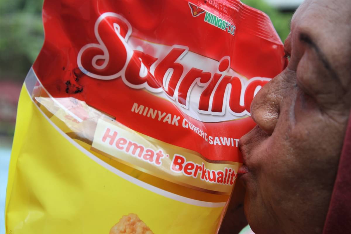 Warga mencium minyak goreng kemasan yang dibelinya setelah mengantre.