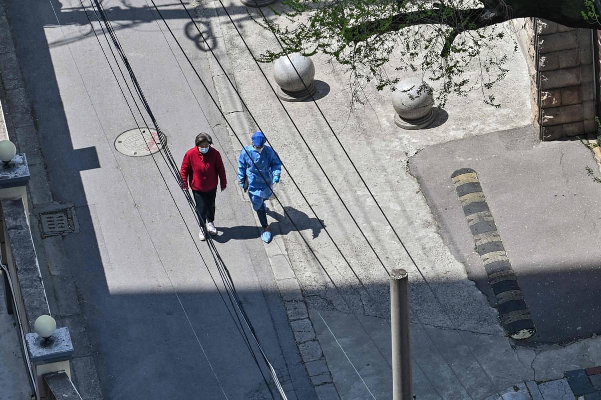Seorang warga dan petugas yang pakai APD mengumpulkan makanan dari warga untuk warga lainnya di Kota Shanghai yang berlakukan 'lockdown'.