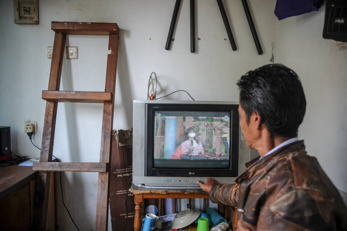 Ilustrasi: Seorang petugas keamanan menonton siaran TV analog