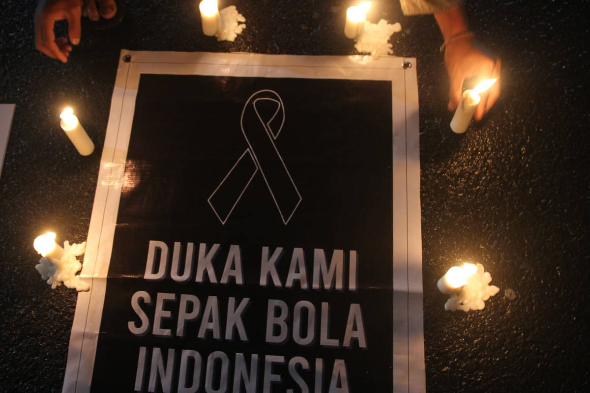 Suporter menyalakan lilin sesaat sebelum doa bersama di Stadion Kanjuruhan, Malang.