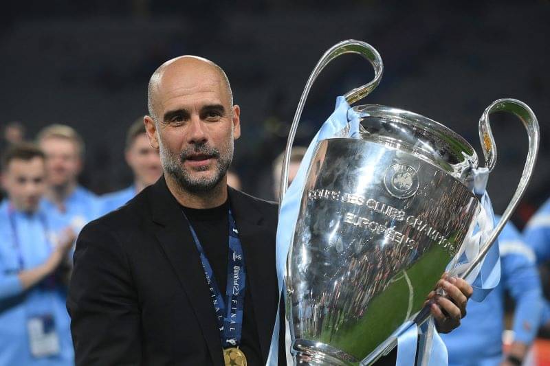 Pep Guardiola menggendong trofi Liga Champions.
