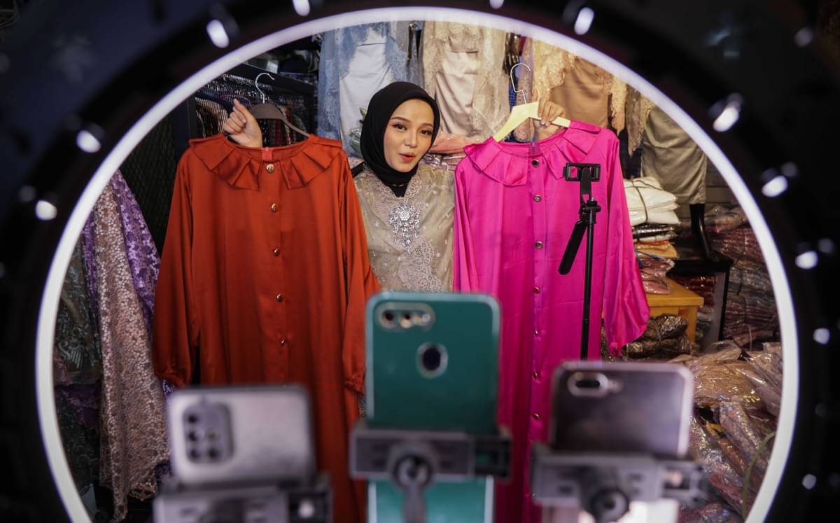 Seorang pedangan sedang melakukan live streaming untuk menjual dagangannya di e-commerce