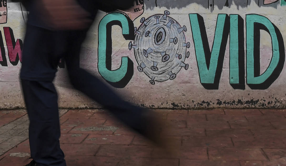 Warga berjalan di dekat mural bertema pencegahan penyebaran covid-19.