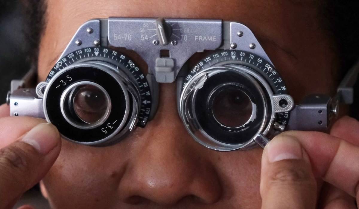 Dokter memasangkan lensa kacamata minus saat memeriksa kondisi mata seorang warga.