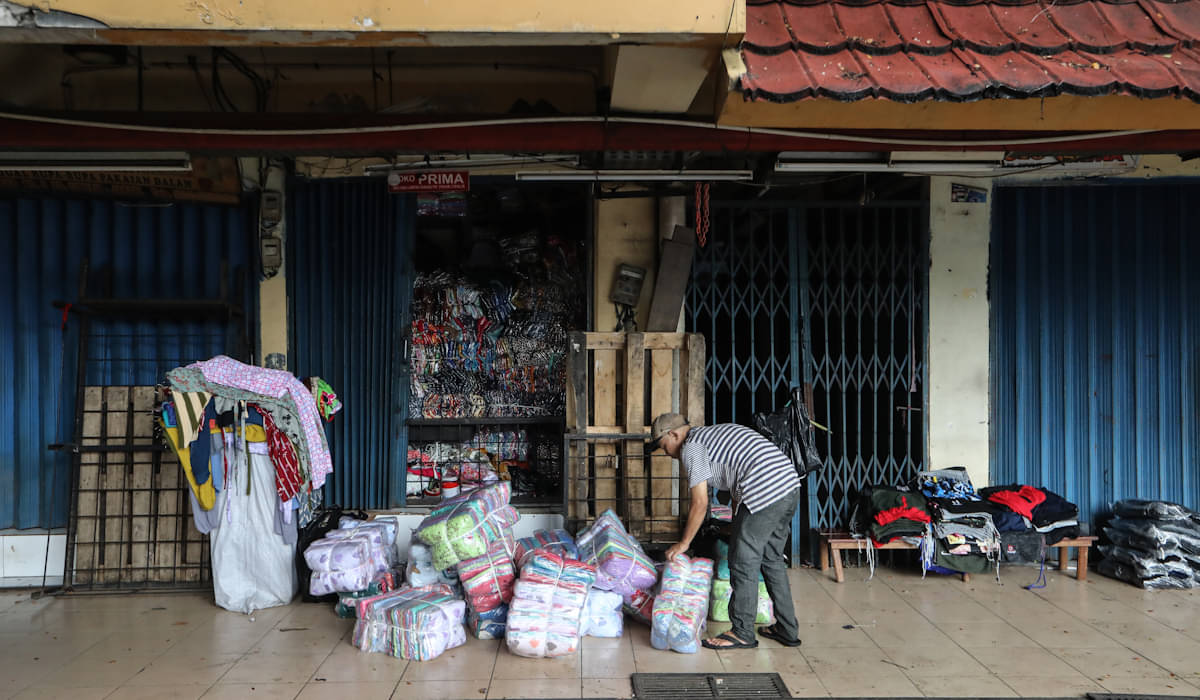 Pedagang pakaian menggelar dagangannya di depan toko yang masih tutup di Pasar Cipulir 