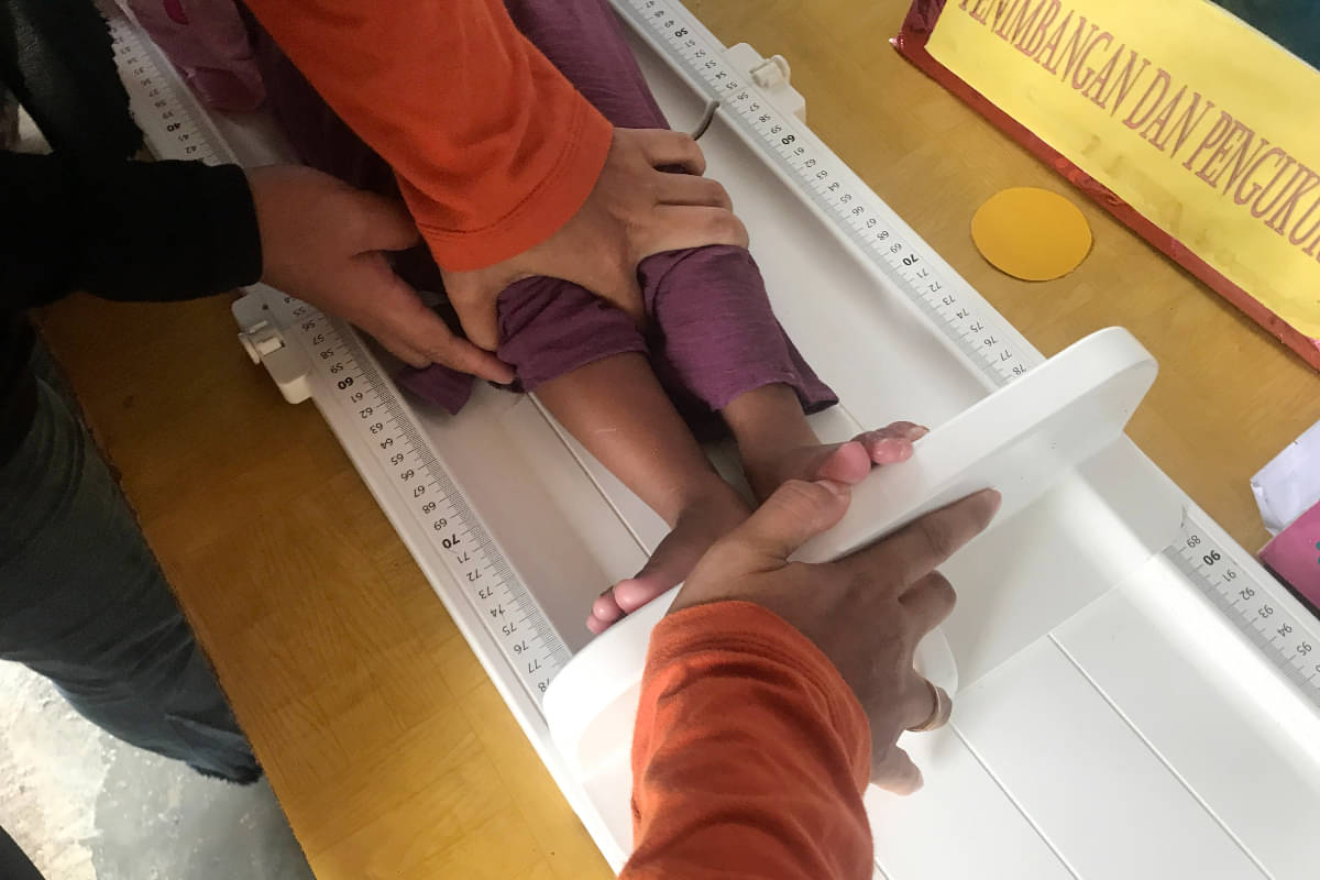 Kader Posyandu menahan kaki seorang balita saat diukur menggunakan alat pengukur tinggi badan di Posyandu Sedap Malam, Kelurahan Pengawu, Pa