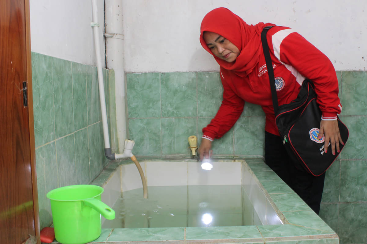 Seorang kader Juru Pemantau Jentik (Jumantik) memeriksa bak penampungan air.
