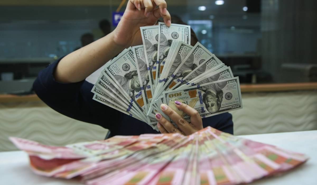 Petugas menunjukkan uang pecahan dolar dan rupiah di gerai penukaran mata uang asing di Jakarta 