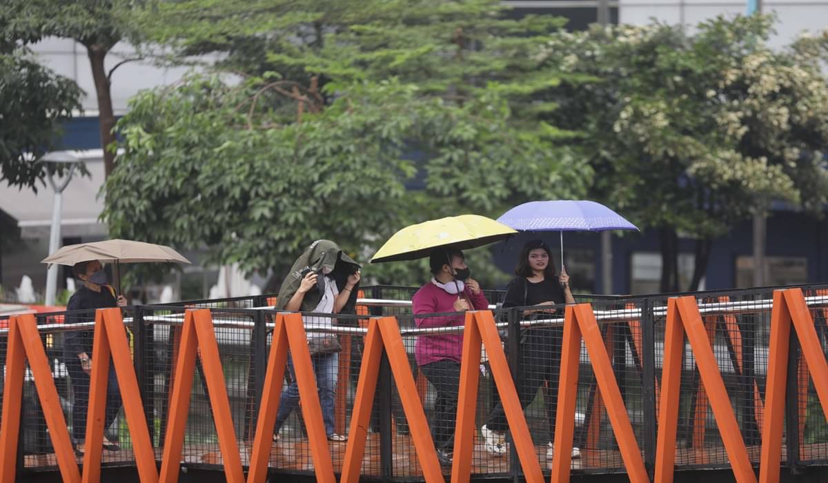 Ilustrasi--Pekerja menggunakan payung saat hujan di kawasan Sudirman, Jakarta.