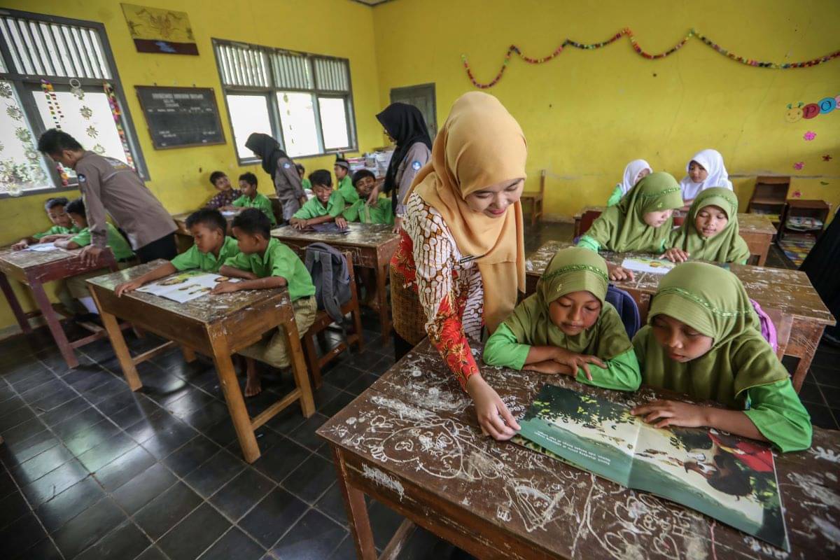 Mahasiswa dari program Kampus Mengajar berkolaborasi dengan guru memberikan materi kepada murid sekolah dasar.