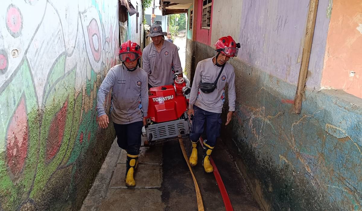 Petugas membantu warga membersihkan lingkungan paska banjir bandang di kawasan Rawa Jati, 