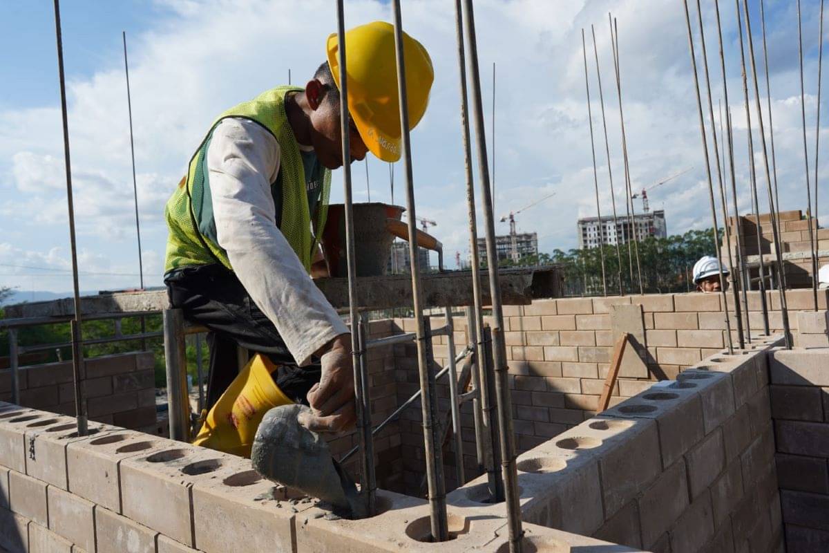 Pekerja sedang membangun rumah menggunakan bata interlock.