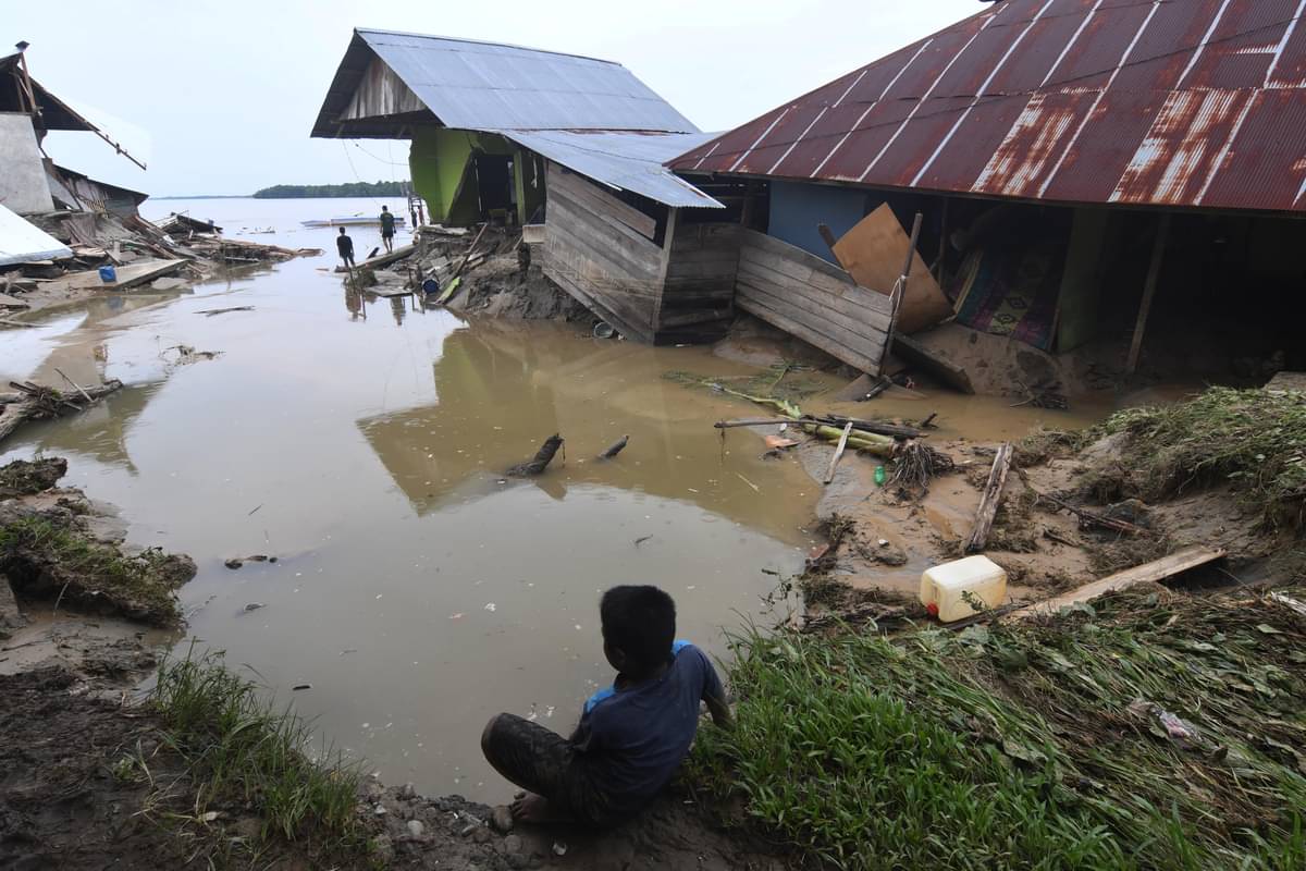 Warga berada di sekitar rumah yang rusak akibat diterjang banjir bandang
