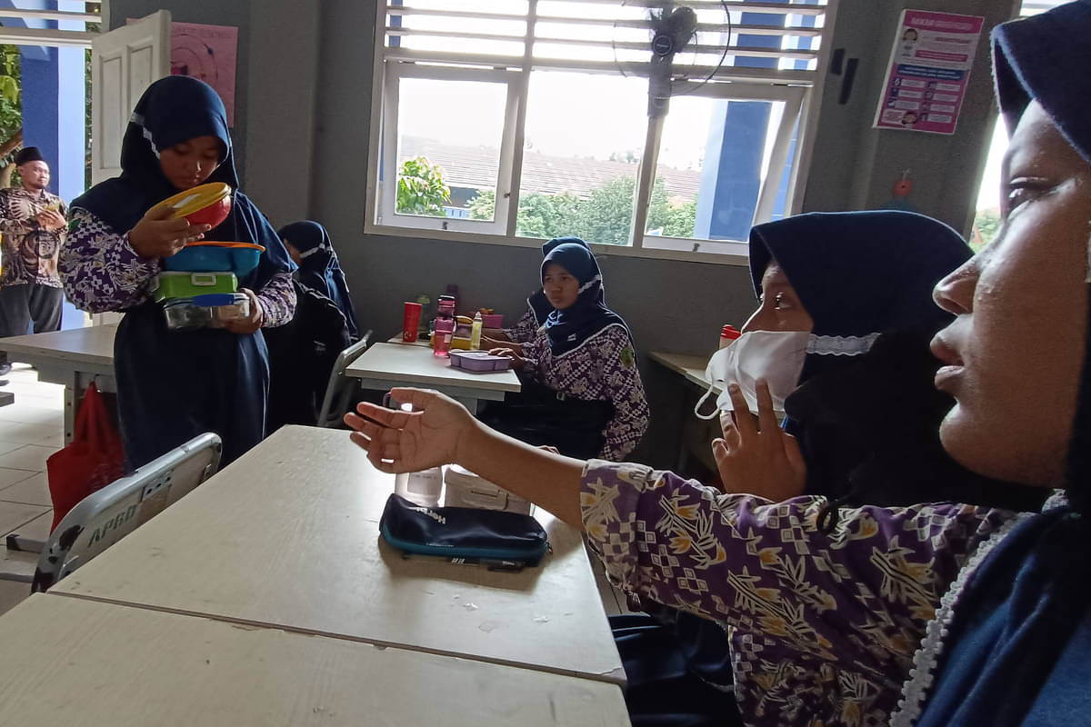 Perwakilan kelas membagikan kotak makan simulasi makan siang gratis