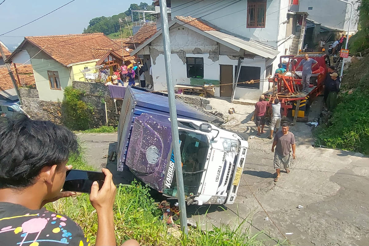Sebuah truk mengangkut kopi terguling di jalur alternatif Dago Giri Lembang, Kabupaten Bandung Barat.