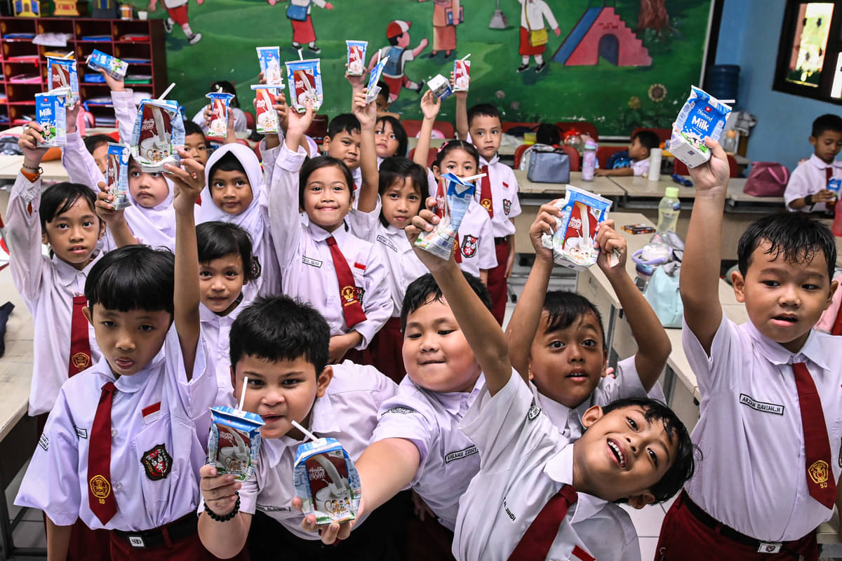 Sejumlah siswa menunjukkan susu kemasan saat uji coba program makan bergizi gratis